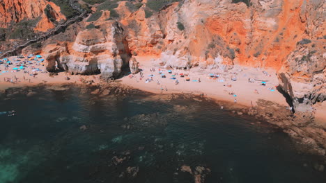 Gente-Caminando-Por-La-Playa-Durante-El-Verano-En-Praia-Dona-Ana-En-El-Algarve-En-Portugal,-Vista-Aérea-De-Drones