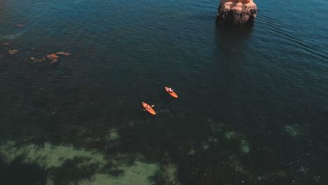 People-kayaking-in-the-ocean-during-the-summer-in-Praia-Dona-Ana-in-the-Algarve-in-Portugal,-aerial-drone-view