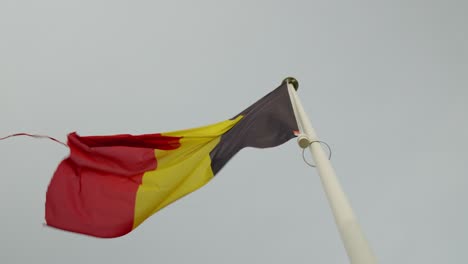 Bandera-Belga-Rota-Ondeando-Contra-El-Cielo-Nublado---Concepto-De-Partición-Del-País-Bélgica,-Separación-De-Regiones,-Referéndum
