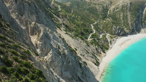 Drone-flyover-forested-rocky-cliffs-revealing-pristine-turquoise-water-in-the-Myrtos-Beach,-Greece
