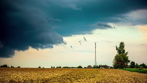 Stürmische-Wolken-über-Ackerfeldern-Und-Einem-Mobilfunkmast-Auf-Dem-Land---Zeitraffer