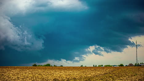 Farm-field-with-a-stormy,-dark,-dramatic-cloudscape-time-lapse