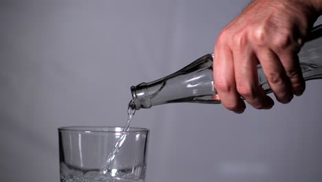 Hand-Holding-Water-Bottle-and-Pouring-Isolated-on-Grey-Background