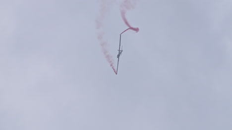 Swift-S-1-falling-from-sky-stunt-with-red-smokes,-view-from-bellow