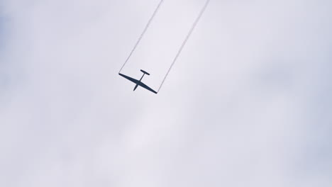 Swift-S-1-glider-with-smoke-trail-in-the-sky-doing-stunts,-follow-view