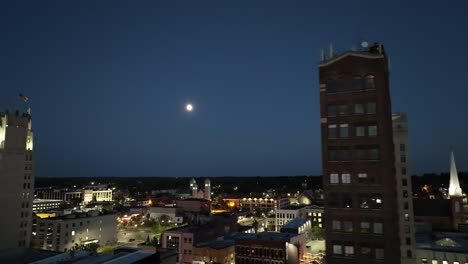 Jackson,-Michigan,-Centro-De-La-Ciudad-Por-La-Noche-Con-Video-De-Drones-De-Cerca-Con-La-Luna-Moviéndose-De-Derecha-A-Izquierda