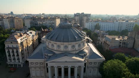 Top-Down-View-Over-The-Romanian-Athenaeum-At-Sunrise-In-Bucharest-Surrounded-By-Tall,-Historic-Buildings