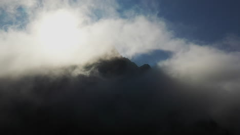 Filmische-Drohnenaufnahme-Von-Wolken-Auf-Berggipfeln,-Wobei-Die-Sonne-Schatten-In-Die-Wolken-Wirft
