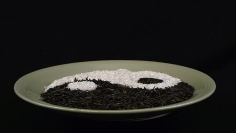 Plate-of-rice-in-yin-yang-design-revolves-against-black-background