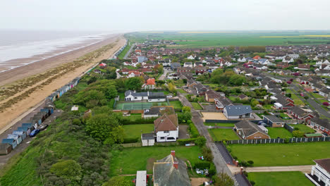 Discover-the-coastal-haven-of-Mablethorpe-through-aerial-views,-spotlighting-beach-huts,-sandy-beaches,-amusement-parks,-rides,-and-the-tourist’s-delight