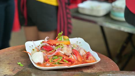 Zooming-out-of-the-frame-on-a-plateful-of-Somtam-Thai-papaya-salad,-taken-by-a-customer-from-the-left-from-a-local-hawker-in-the-streets-of-Bangkok,-Thailand