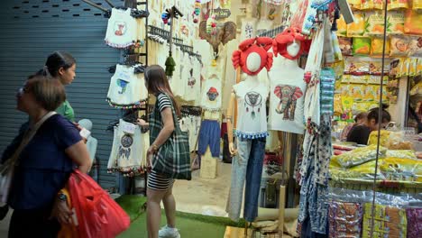 Auswahl-Möglicher-Souvenirs-Wie-Hemden,-Hosen-Und-Einige-Delikatessen-Von-Einem-örtlichen-Händler-Auf-Dem-Chatuchak-Wochenendnachtmarkt-In-Bangkok,-Thailand