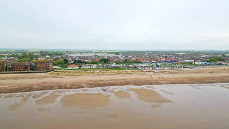 See-Mablethorpe's-coastal-allure-like-never-before-in-aerial-video,-showcasing-beach-huts,-sandy-beaches,-amusement-parks,-rides,-and-the-holidaymakers'-joy
