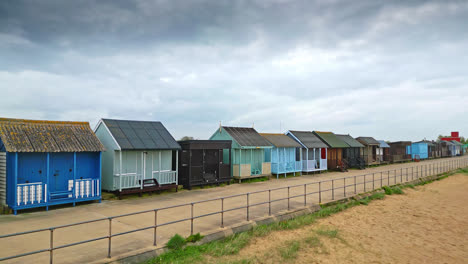 Explore-Mablethorpe-from-above,-revealing-beach-huts,-sandy-shores,-amusement-parks,-rides,-and-the-bustling-holiday-crowd