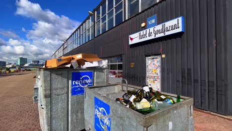 Waste-bin-with-empty-wine-bottles-in-front-of-restaurant-Goudfazant-in-Amsterdam-North