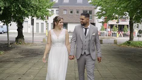 Newlywed-couple-walking-while-holding-hands-in-urban-environment