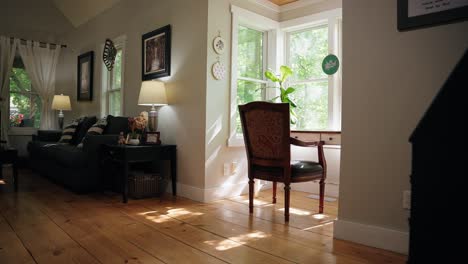 A-small-desk-with-an-old-chair-setup-in-a-nook-in-the-living-room,-with-sunlight-shining-through-surrounding-windows-onto-the-desk