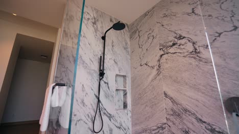 Push-in-shot-of-a-large-luxurious-shower-with-white-stone-granite-finishes