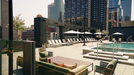 Push-in-shot-of-a-lavish-pool-deck-atop-a-high-rise-building-in-a-bustling-city,-offering-a-luxurious-urban-oasis