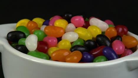 Close-up-revolving-view:-Colourful-Jelly-beans-in-white-bowl-on-black