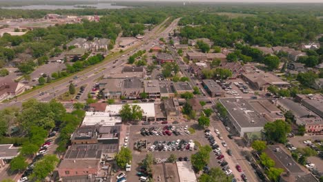 Drone-shot-of-a-vibrant-downtown-area-in-a-quaint-small-town,-capturing-the-lively-atmosphere-and-bustling-streets