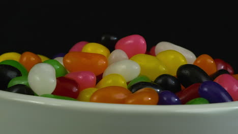 Close-up-view:-Jelly-beans-pile-up-in-revolving-bowl-in-dark-room