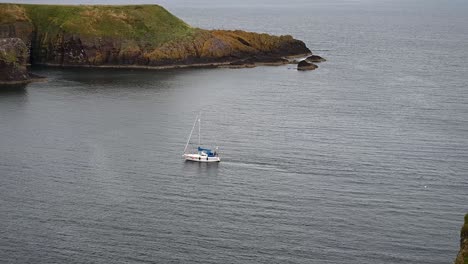 Sailing-away-from-Dunnottar-Castle,-Scotland,-United-Kingdom