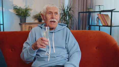 Fröhlicher-älterer-Großvater-Hält-Ein-Glas-Champagner-In-Der-Hand,-Jubelt,-Trinkt-Und-Feiert-Den-Erfolgssieg