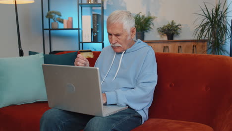 Senior-elderly-man-using-credit-bank-card-and-laptop,-transferring-money,-purchases-online-shopping