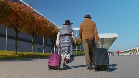 Turistas-Jubilados-Mayores-Abuela-Abuelo-Caminando-Al-Vestíbulo-Del-Aeropuerto-Con-Equipaje-Sobre-Ruedas