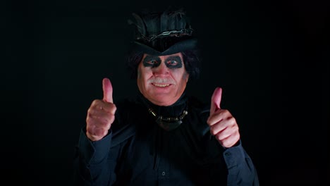 Sinister-elderly-man-with-scary-Halloween-witcher-makeup-in-costume-raises-thumbs-up-like-gesture
