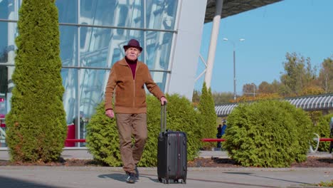 Retired-grandfather-businessman-walking-with-luggage-suitcase-bag-to-airport-hall-or-railway-station