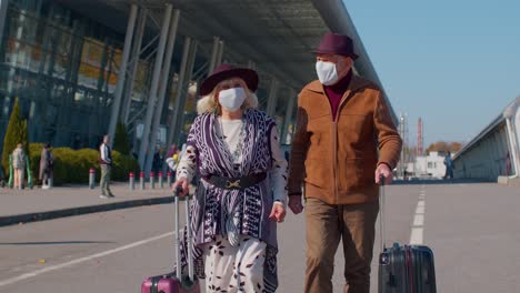 Senior-pensioner-tourists-grandmother-grandfather-walking-from-airport-with-luggage,-coronavirus