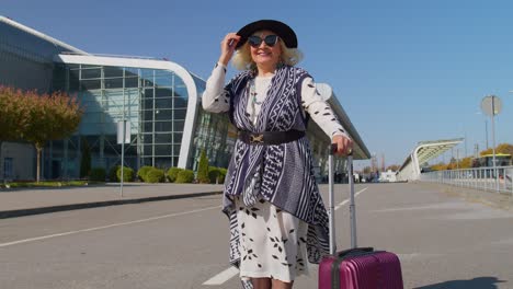 Retired-grandmother-businesswoman-walking-with-luggage-suitcase-bag-to-airport-hall,-railway-station