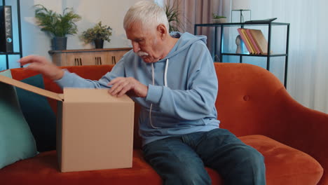 Glücklicher-älterer-Mann,-Der-Den-Karton-Auspackt,-Lieferung-Eines-Pakets-Online-Kauft-Und-Zu-Hause-Einkauft