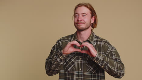 Smiling-blonde-man-makes-heart-gesture-demonstrates-love-sign-expresses-good-feelings-and-sympathy