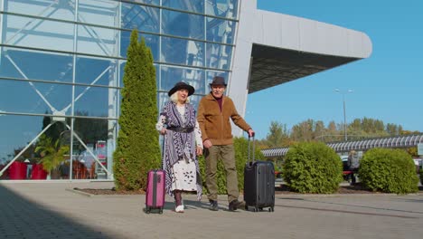 Turistas-Jubilados-Mayores-Abuela-Abuelo-Caminando-Desde-La-Sala-Del-Aeropuerto-Con-Equipaje-Sobre-Ruedas