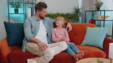 Young-man-father-having-trustworthy-conversation,-talking-with-daughter-child-kid-at-home-sofa