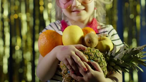 Close-up-shot-of-girl-in-stylish-sunglasses-posing-looking-at-camera-with-bunch-of-fruits-in-hands