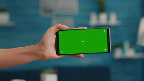 Close-up-of-woman-hands-holding-horizontal-mock-up-green-screen-chroma-key-smartphone