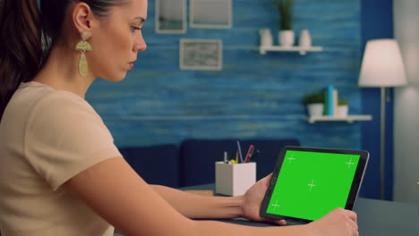 Woman-working-at-office-desk-using-mock-up-green-screen-tablet-computer