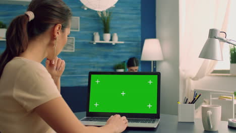 Freelancer-looking-at-laptop-computer-with-mock-up-green-screen-chroma-key-display