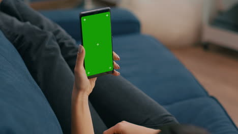 Freelancer-holding-in-vertical-mode-smartphone-with-mock-up-green-screen-chroma-key-display