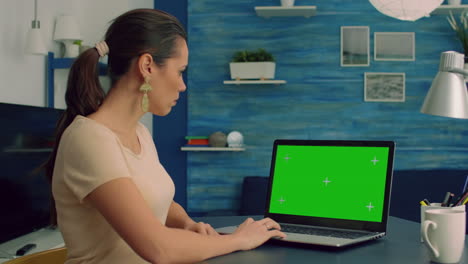 Caucasian-female-typing-on-laptop-computer-with-mock-up-green-screen-chroma-key-display