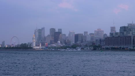 Downtown-Montreal,-Quebec,-Skyline-from-Across-the-St-Lawrence-River-on-a-Cloudy-Evening-with-Beautiful-City-Night-Lights