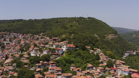 Hillside-city-of-Veliko-Tarnovo-aerial-flight-towards-woodland-hilltop
