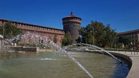 Tourists-walking-past-Fountain-of-Piazza-Castello-in-front-of-Sforza-Castle,-Milan