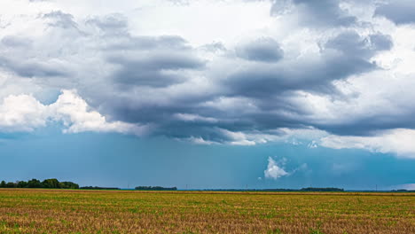 Zeitraffer-Der-Sich-Entwickelnden-Wolkenformationen-über-Lettlands-Ackerland,-Während-Ein-Traktor-über-Die-Landschaft-Fährt