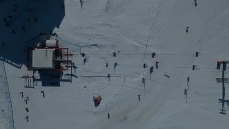 Top-down-dolly-shot-of-people-skiing-down-the-El-Colorado-ski-slope-with-people-using-the-ski-lift