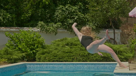 Girl-in-black-swimming-costume-loses-balance-and-falls-into-swimming-pool-in-slow-motion